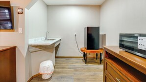 A compact kitchen with a sink, a television on a stand, and a wooden cabinet. - Ski, Explore! Studio 5 Mi to Pine Knob (Clarkston)
