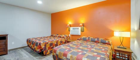 A hotel room with two beds, a desk, and a lamp.