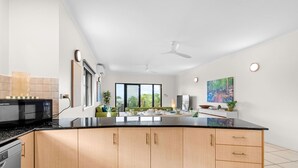 Eine moderne Küche mit schwarzem Arbeitsplatz, Holzschränken, einer Mikrowelle und einem Essbereich mit Tisch und Stühlen.