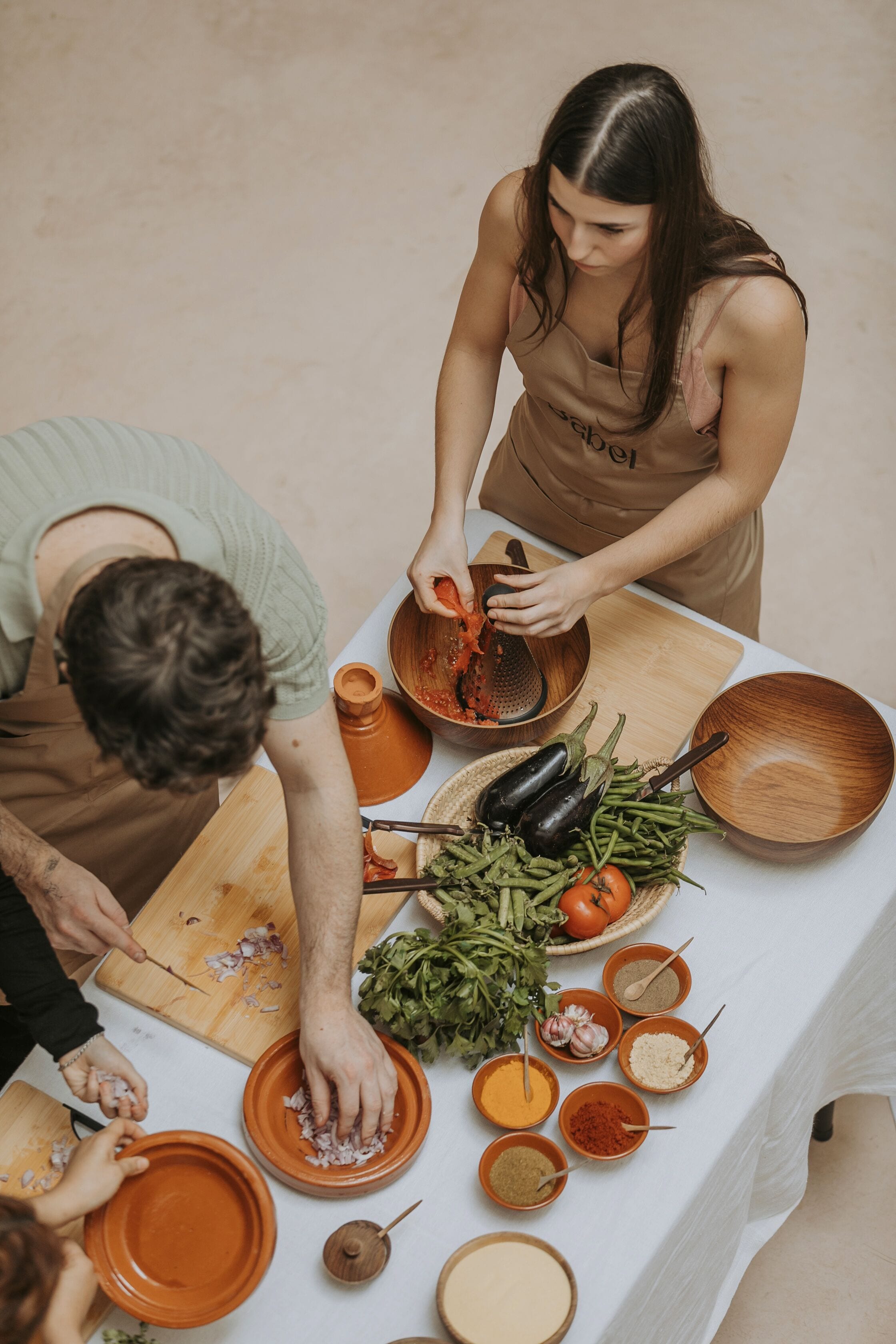 A group of people preparing food at a table with various ingredients and cooking utensils.