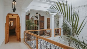 A multi-level interior with a wooden staircase, white walls, and a balcony with a wrought iron railing. - Riad Babel (Marrakech)