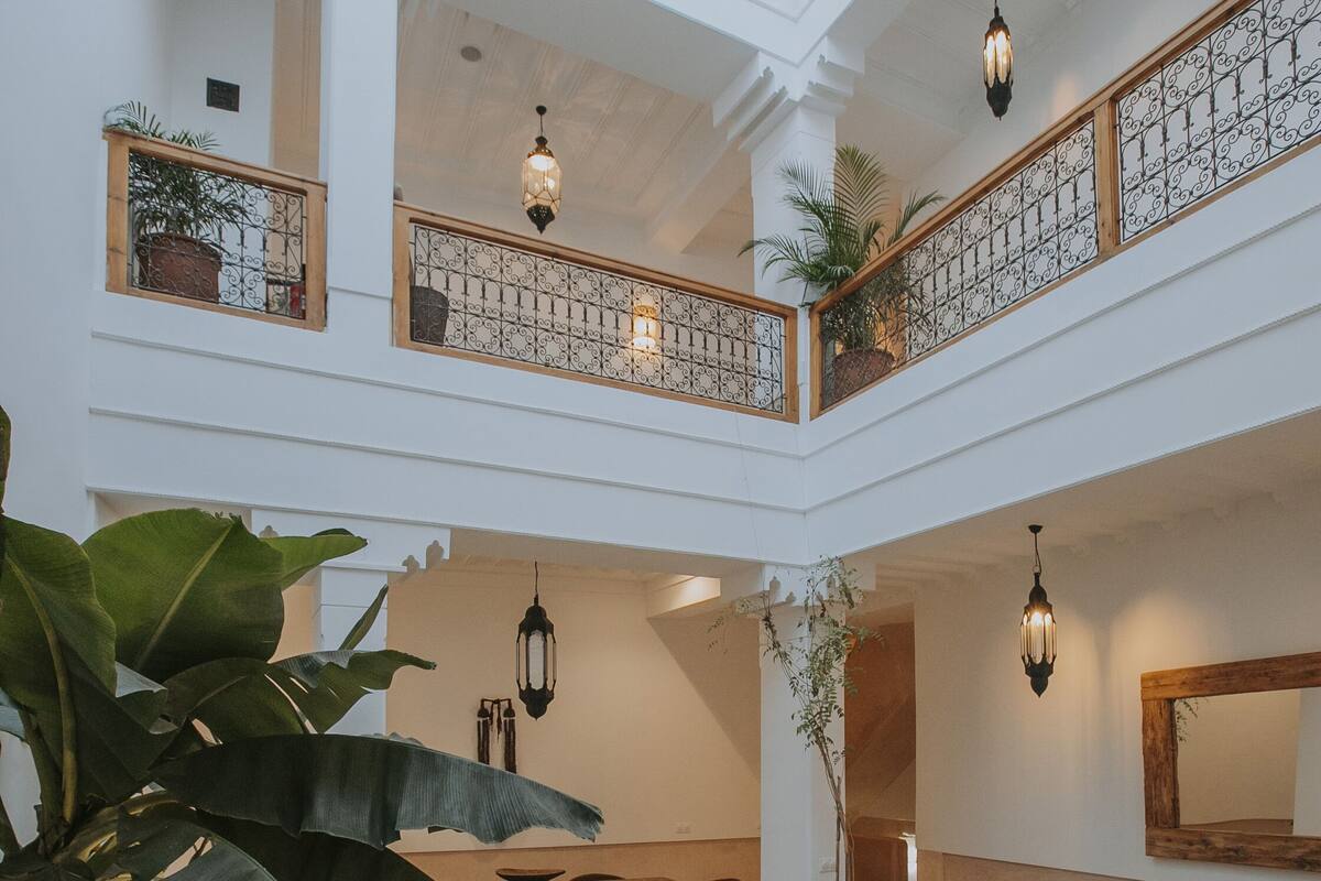 A spacious atrium with a central water feature, multiple seating areas, and a balcony with railings and plants.