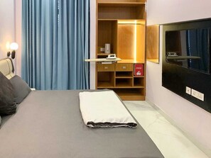 Een hotelkamer met een bed, bureau, kledingkast en televisie.