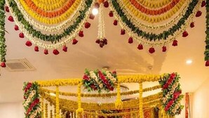 A decorated indoor space with a central structure adorned with floral garlands and a patterned carpet. - AKD HOMES (Noida)