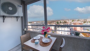 A balcony with a table set for two, a Baxi air conditioning unit, and a view of a cityscape. - WELCS ESTUDIO 308 EMP near the sea (Empuriabrava)