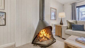 A cozy living room with a wood-burning stove, a sofa, a coffee table, and a lamp. - Freshly Updated Condo, Across The Street From The Resort Edel O 2 Bedroom Apts (Park City)