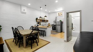 Eine moderne Küche mit weißen Wänden, einem Holztisch und schwarzen Stühlen. Ein eingebauter Ofen und ein Kühlschrank sind vorhanden.