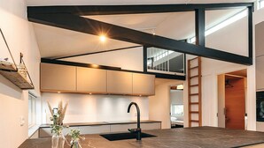 Een moderne keuken met een zwart aanrecht, een zwarte spoelbak en een houten balk.