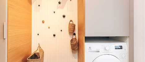 A laundry area with a washing machine, a bench, and wall-mounted baskets.