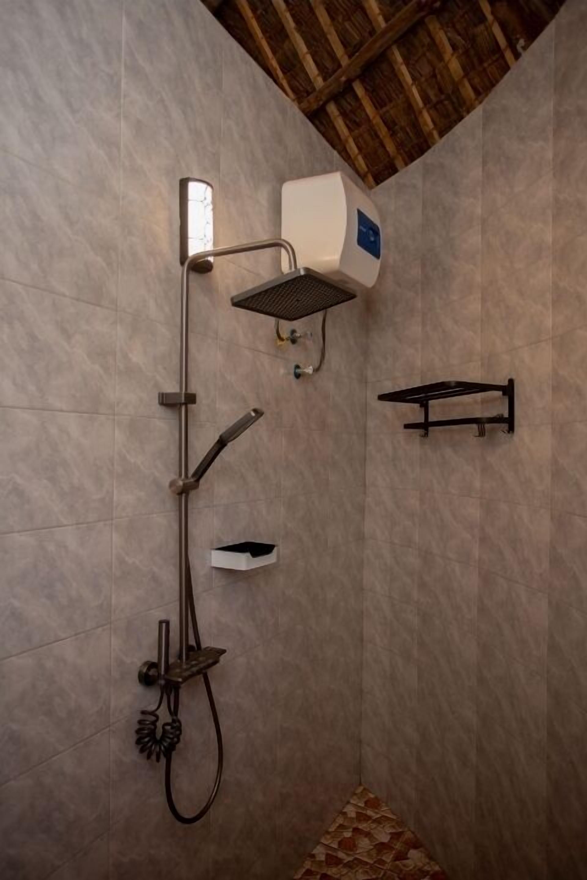Eine Dusche mit Duschkopf, Bedienfeld an der Wand und Handtuchhalter.
