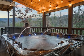 A hot tub with a wooden deck and a view of the mountains. - New- Wildside Cabin, All Sport Simulator, Hot Tub & Views (Pigeon Forge)