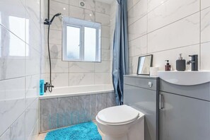 A modern bathroom with a bathtub, toilet, and sink. - Stylish Spacious 3-Bed Sheffield Home (Highfield)