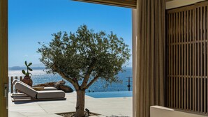 A modern outdoor area with a lounge chair, a small tree, and a view of the sea. - Villa Noema - Seaside Living Redefined (Agiassos)