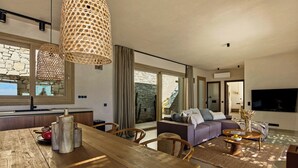A modern living room with a wooden dining table, a sofa, and a TV. - Villa Noema - Seaside Living Redefined (Agiassos)