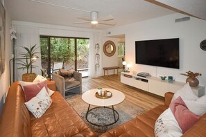 Una sala de estar moderna con un sofá de cuero, una mesa de centro redonda y un televisor de pantalla plana montado en la pared.