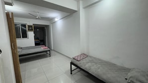 Un dormitorio con dos camas individuales, un ventilador de techo y suelo de baldosas.
