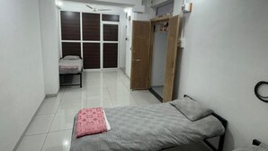 Un dormitorio con dos camas, un armario, una puerta que da a un balcón y un ventilador de techo.