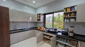 Une cuisine moderne avec des meubles gris, un plan de travail noir et une fenêtre donnant sur un paysage verdoyant.