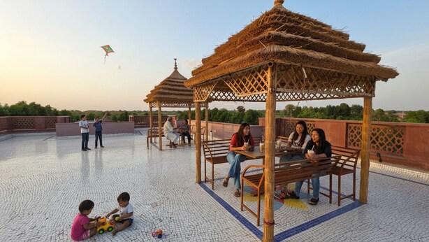 Un kiosque doté d’un toit de chaume, entouré d’une terrasse carrelée.