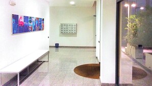 Un couloir avec un banc, un luminaire fixé au mur et une prise de courant.