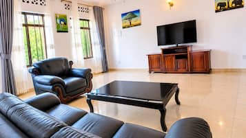 Ein Wohnzimmer mit einer Couch, einem Sessel, einem Couchtisch, einem Fernseher und Kunstwerken an den Wänden.