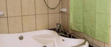 Un baño con una bañera blanca, un cabezal de ducha y una cortina de ducha verde.