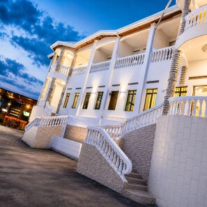 A multi-story hotel with a grand staircase, balconies, and a well-lit facade. - Kivu Go-Lax Resort (Gisenyi)