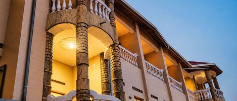 A multi-story building with a grand entrance featuring a balustrade and columns.