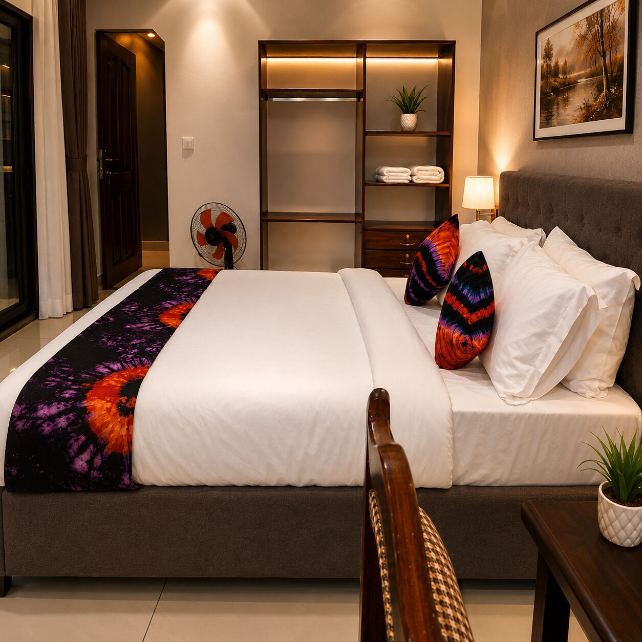 Habitación de hotel con cama, mesita de noche, lámpara y vista al lago.