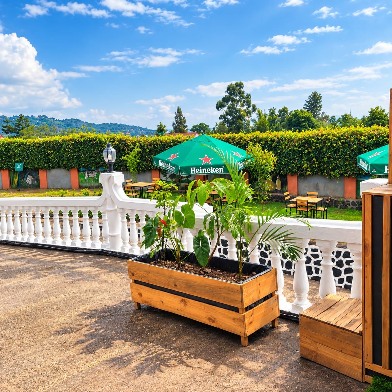 Un espace extérieur aménagé avec des jardinières en bois, des tables et des parasols verts.
