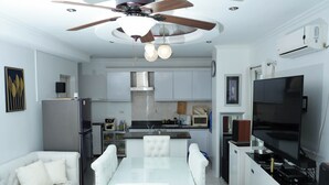 Une cuisine moderne avec un coin repas, des meubles blancs, un ventilateur de plafond et un appareil de climatisation.