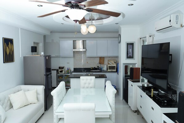 Una cocina moderna con comedor, muebles blancos, ventilador de techo y aire acondicionado.