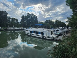 Un río tranquilo con un barco amarrado y otros barcos al fondo.