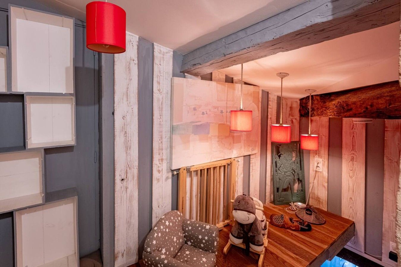 A cozy room with a wooden dining table, a rocking chair, and a small table with a stuffed toy and a pair of shoes.