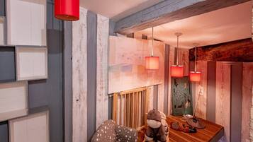 A cozy room with a wooden dining table, a rocking chair, and a small table with a stuffed toy and a pair of shoes.