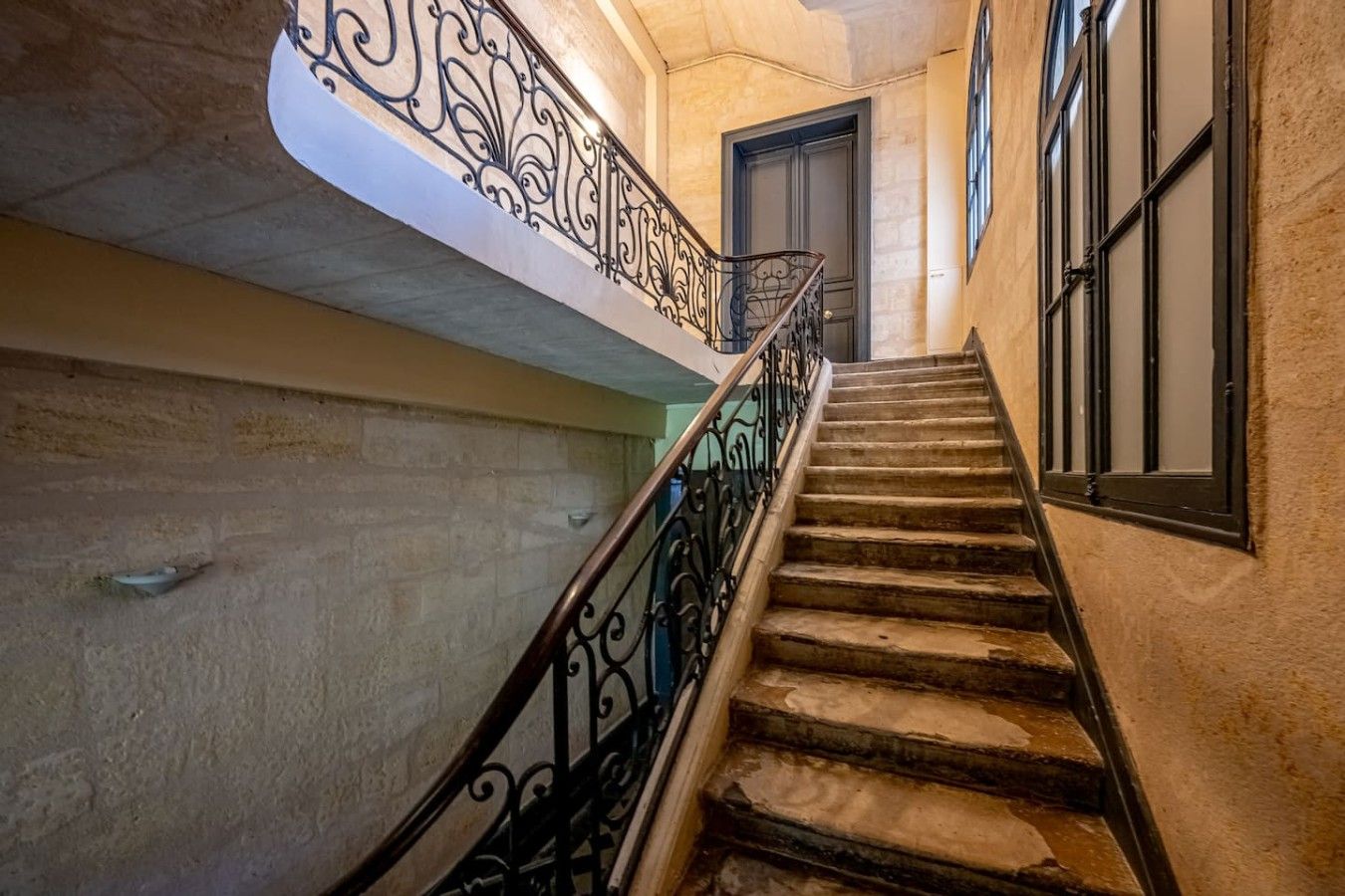 A staircase with ornate metal railings leading to a door.