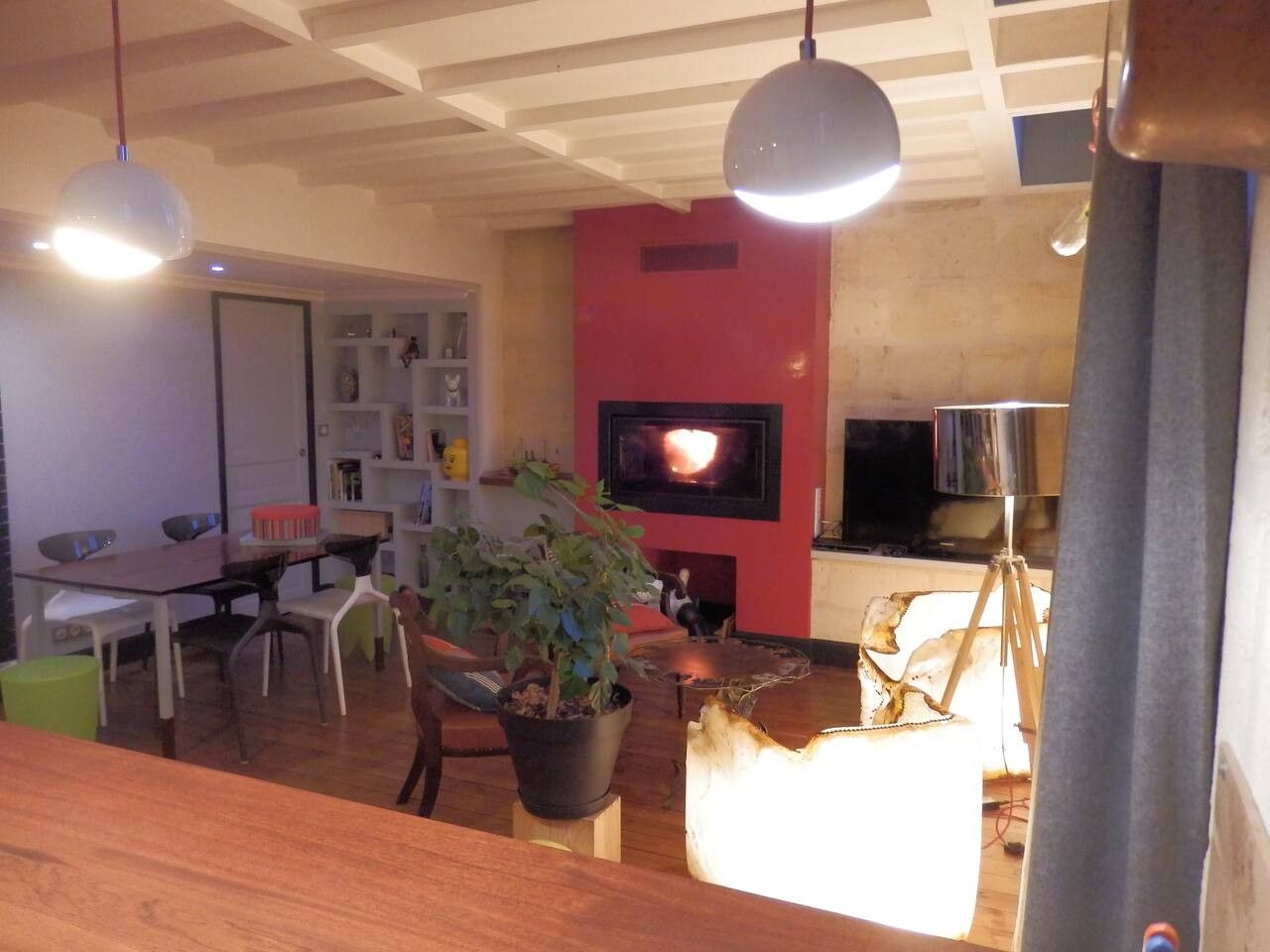 A living room with a fireplace, a dining area with chairs and a table, and a television mounted on the wall.