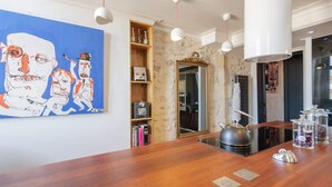 Una cucina moderna con un piano di lavoro in legno, un bollitore e una libreria con libri e bottiglie.