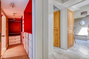 Ein Flur mit einem roten Kleiderschrank und einer Holztür, die in einen Raum mit einem Fenster führt.