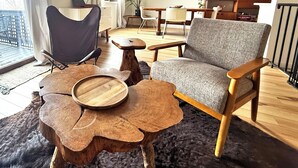 Ein modernes Wohnzimmer mit großem Fenster, Flachbildfernseher, Essbereich und gemütlicher Sitzecke.