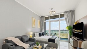 Ein modernes Wohnzimmer mit einer Couch, einem Bett, einem Fernseher und einem Balkon mit Blick auf die Stadt.