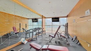 Ein Fitnessstudio mit verschiedenen Trainingsgeräten, darunter Kurzhanteln, Bänke und Kraftgeräte.