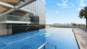 Ein modernes Gebäude mit Glasfassade und einem Poolbereich mit blauen Mosaikfliesen.
