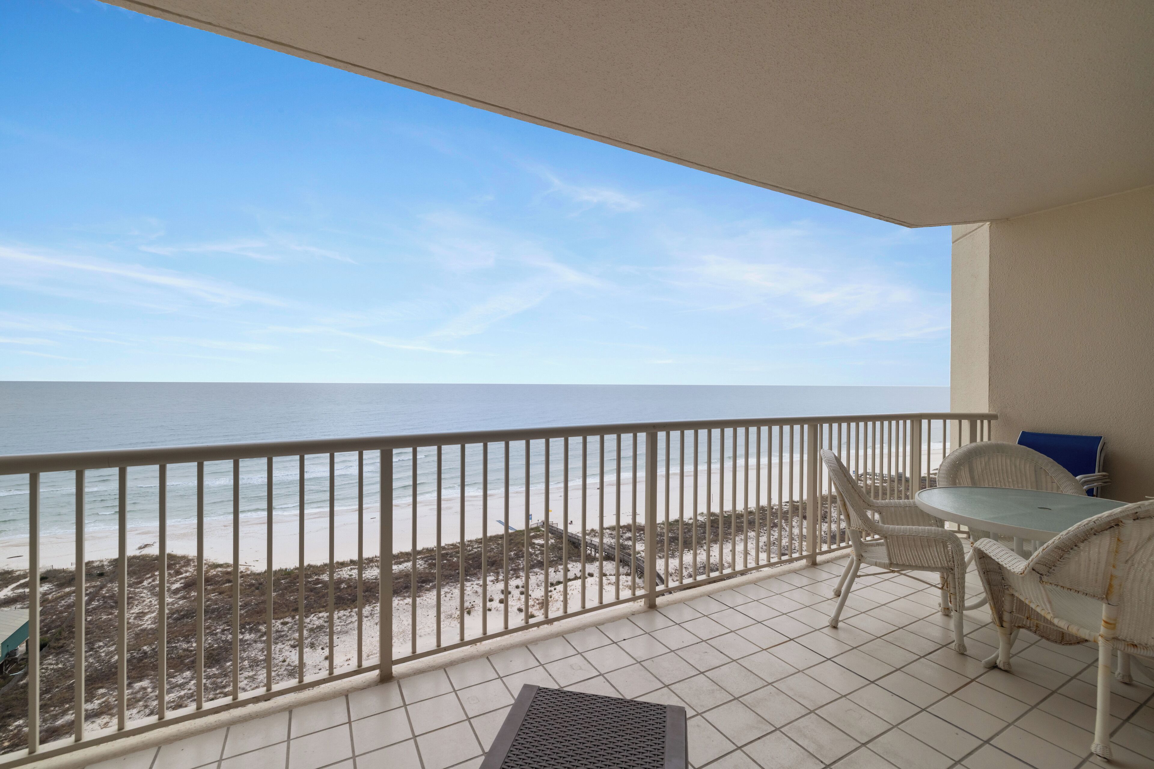 A balcony with a view of the beach and ocean.