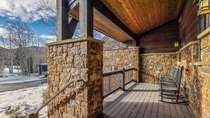 Una terraza de madera con paredes de piedra y barandilla de metal.