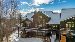 Una casa grande y moderna con terraza y varios niveles, rodeada de nieve.