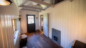 A room with wooden floors, a fireplace, a door, and a window.