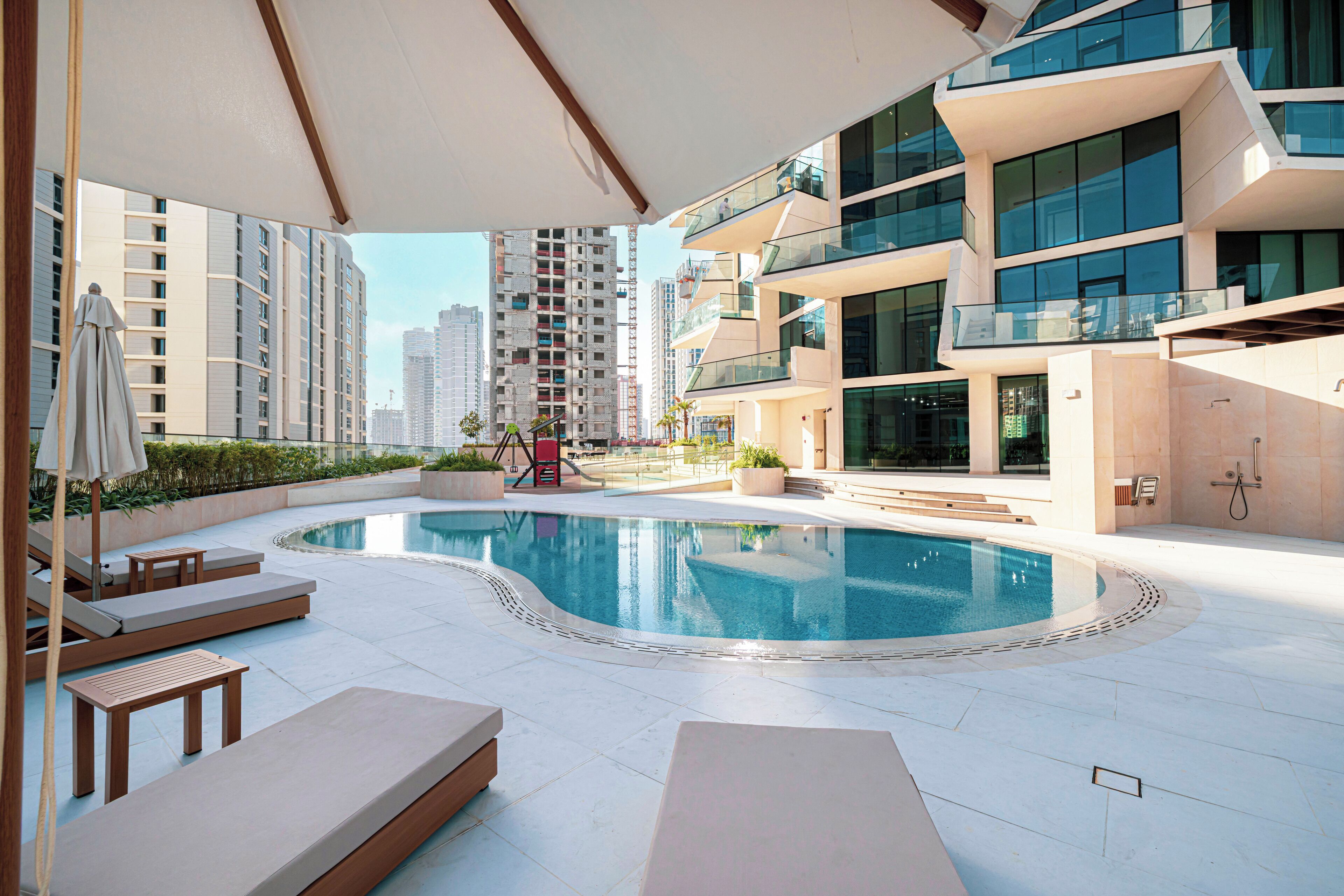 A rooftop pool area with lounge chairs, a small table, and a children's play structure.