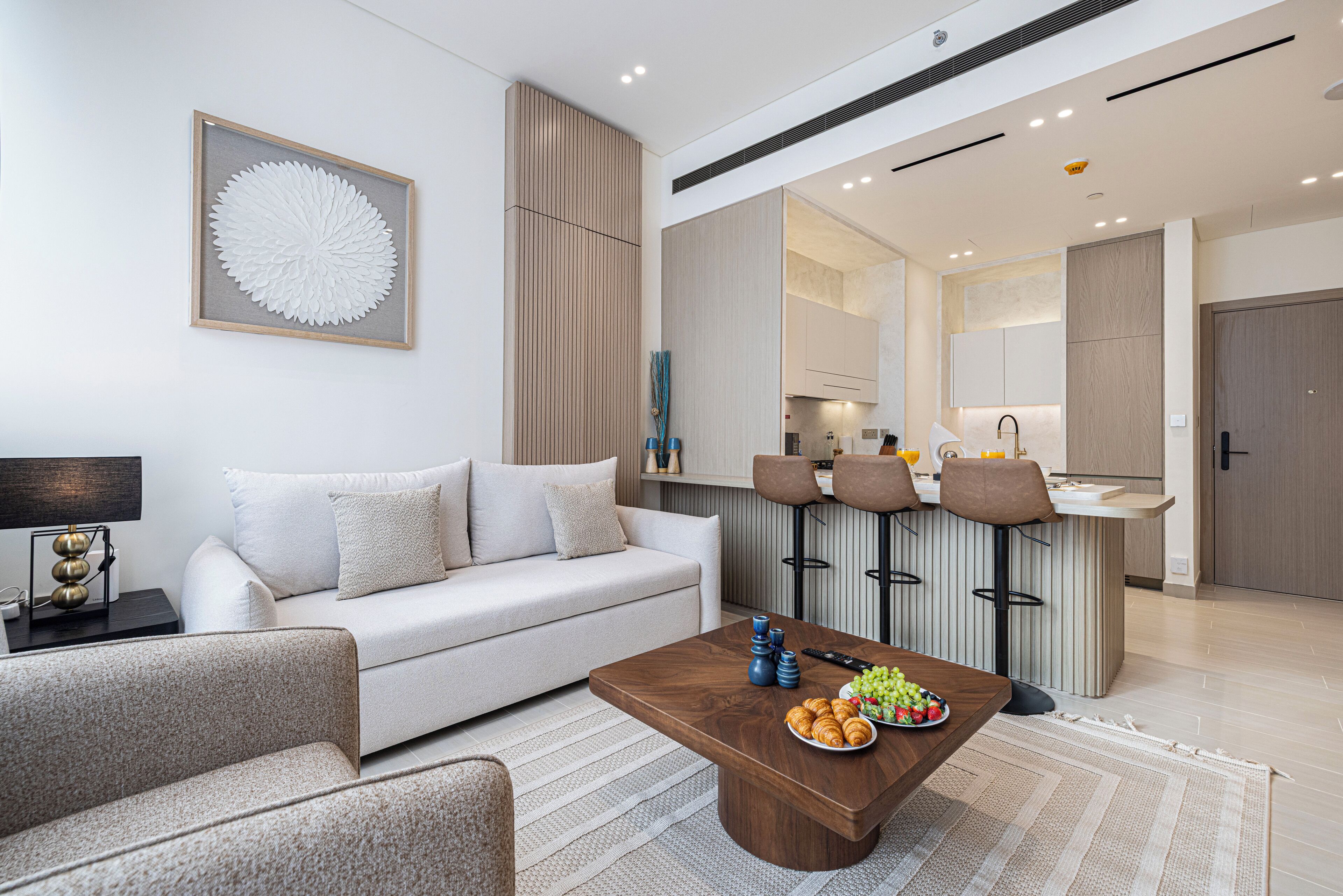 A modern living room with a sofa, coffee table, and a kitchen area in the background.