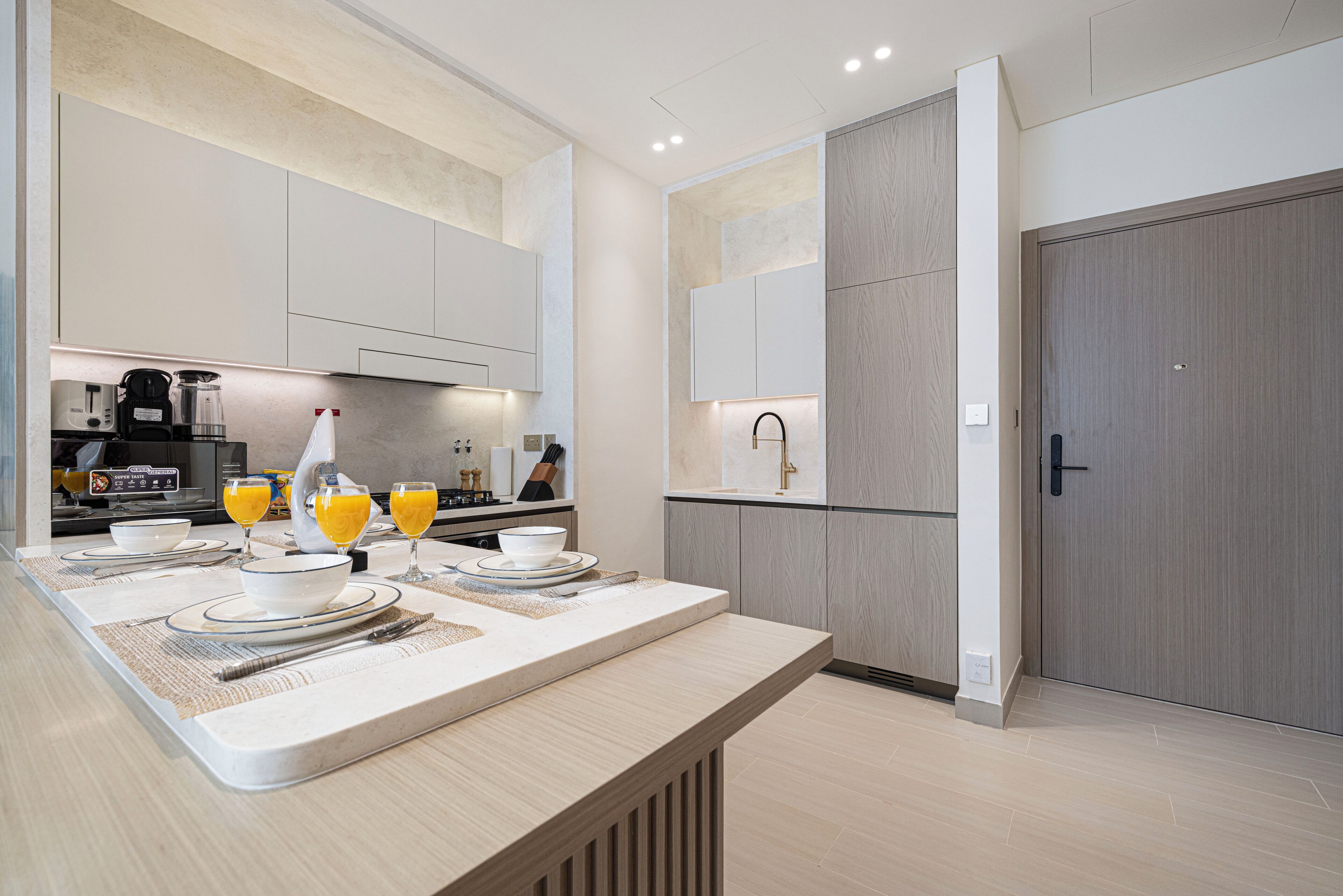 Una cocina moderna con una mesa para el desayuno, que incluye una cafetera, jugo de naranja y alimentos para el desayuno sobre la encimera.